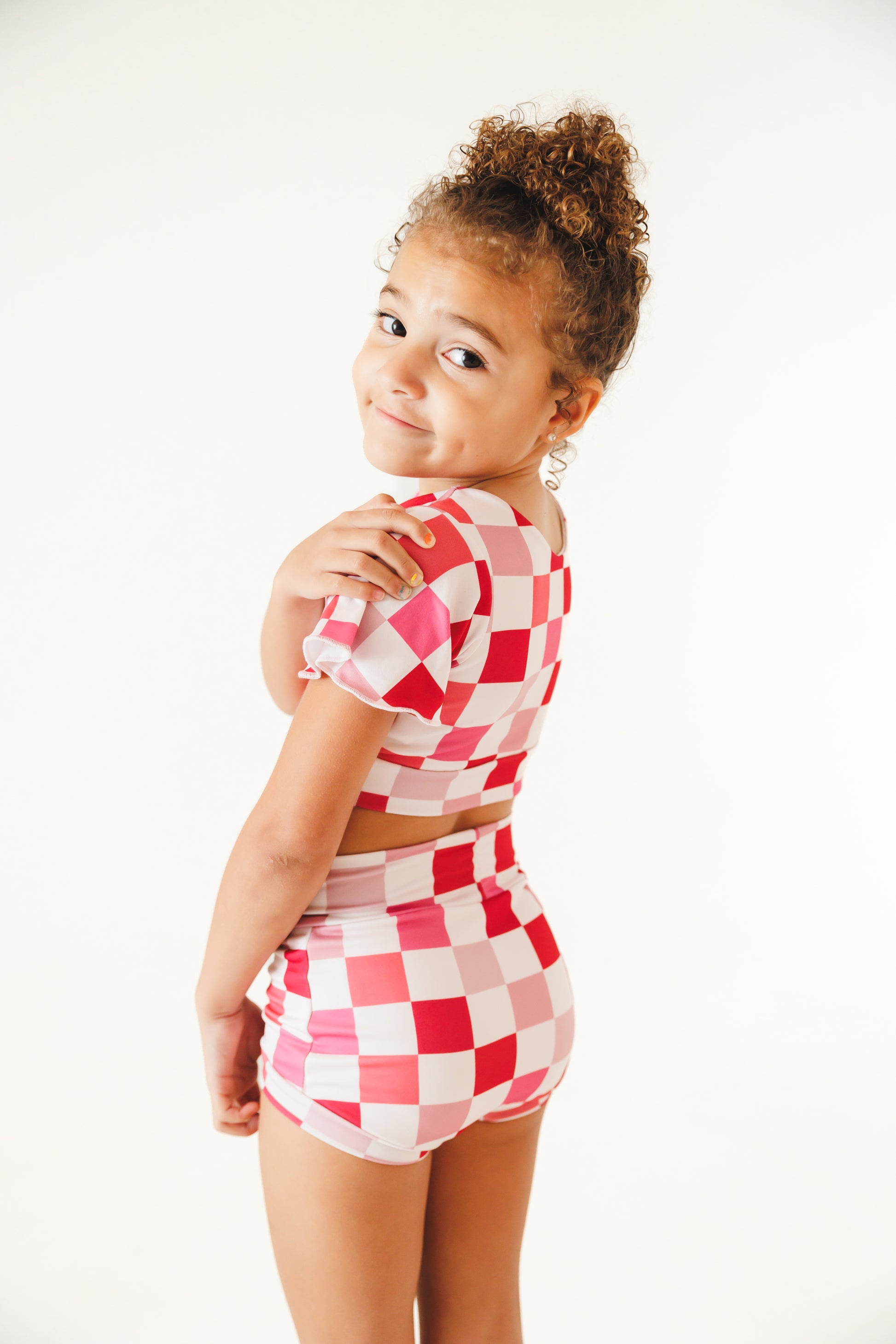 girl wearing pink and white checkered two piece dance outfit