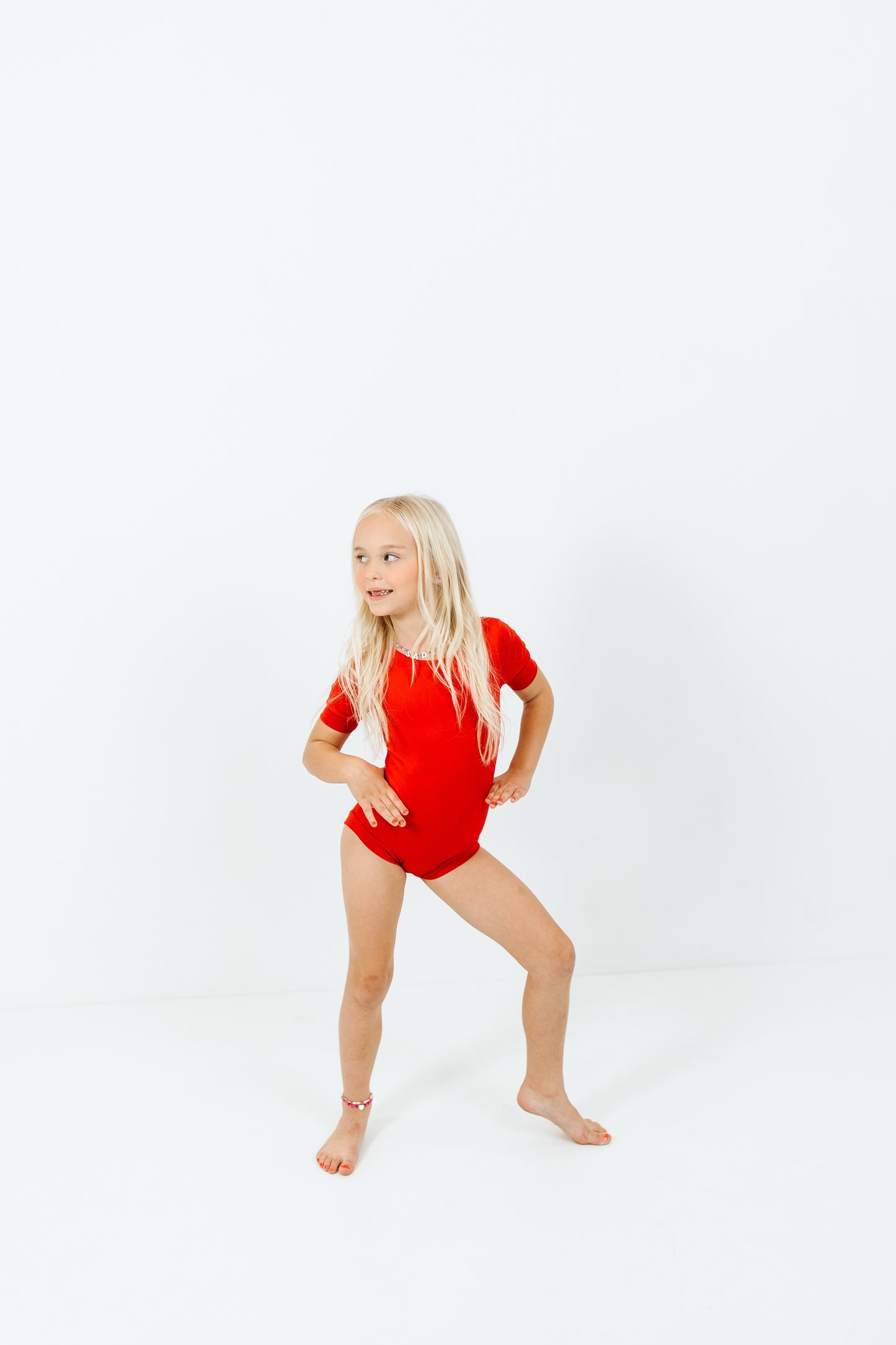 girl wearing red short sleeve leotard on white background