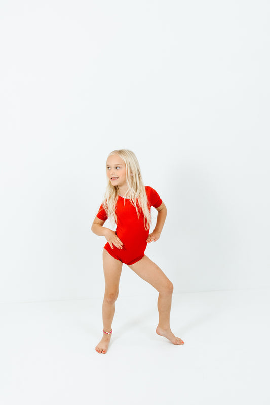 girl wearing red short sleeve leotard on white background